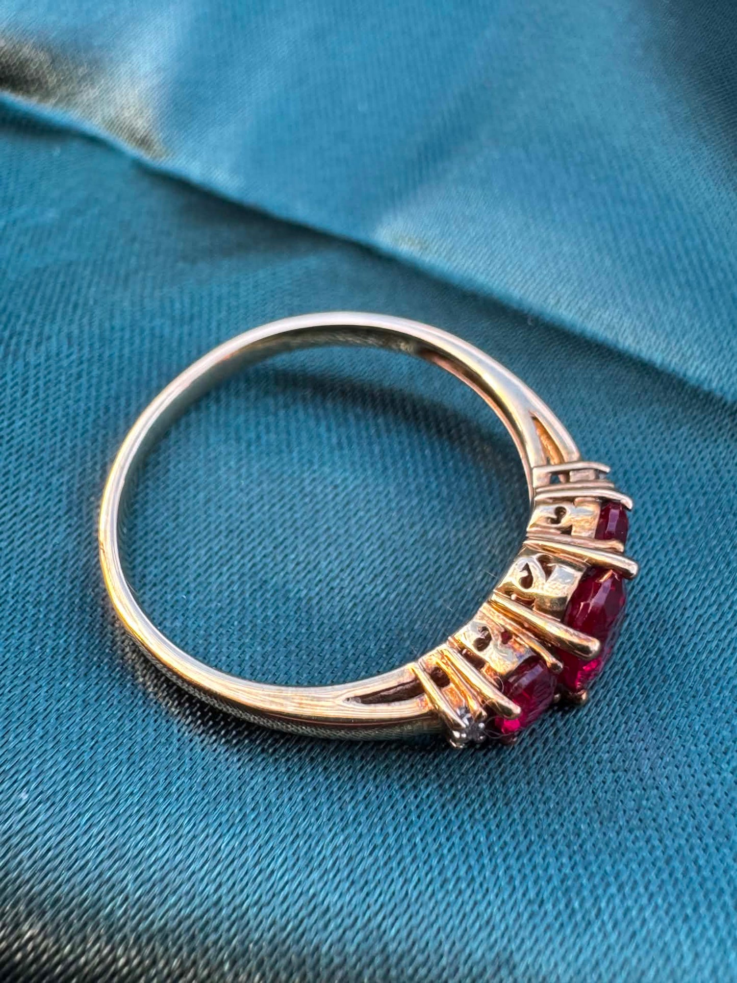 Ruby and diamond trilogy ring in 9ct yellow gold, angled view showing rubies facing down