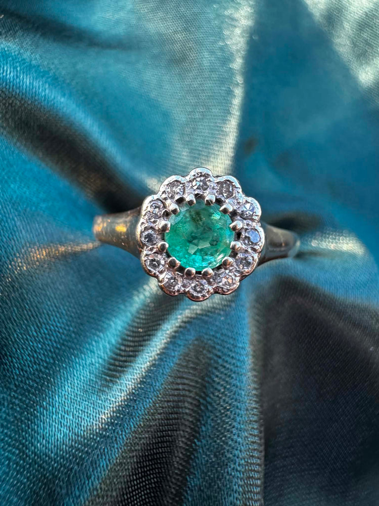 Emerald and diamond halo ring in 9ct yellow gold, overhead view showing round emerald surrounded by diamond halo