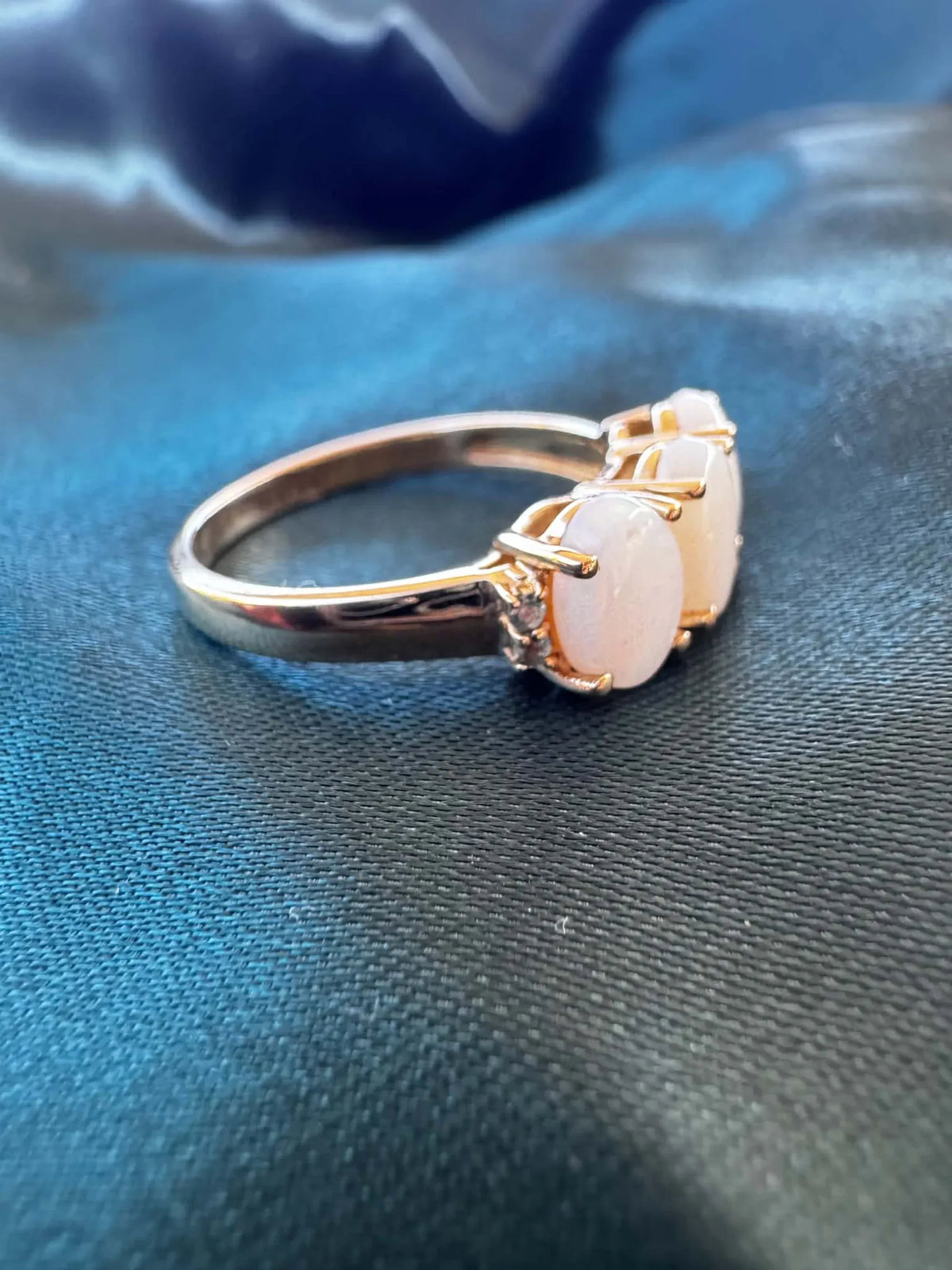 Three-stone white opal ring in 9ct yellow gold, side profile showing the centre white opal cabochon and gold