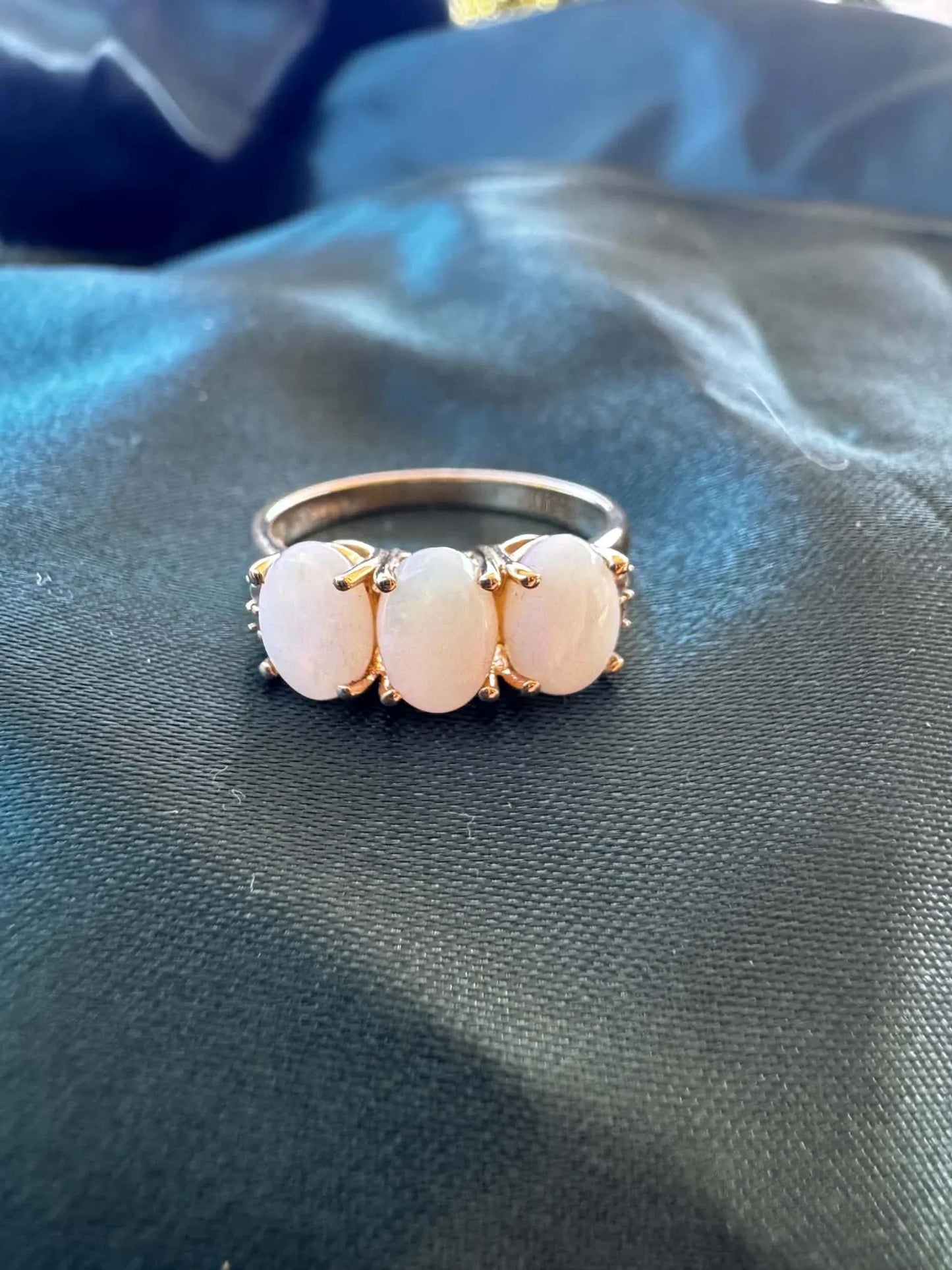 Three-stone white opal ring in 9ct yellow gold, front view showing three oval white opal cabochons in yellow gold claw settings