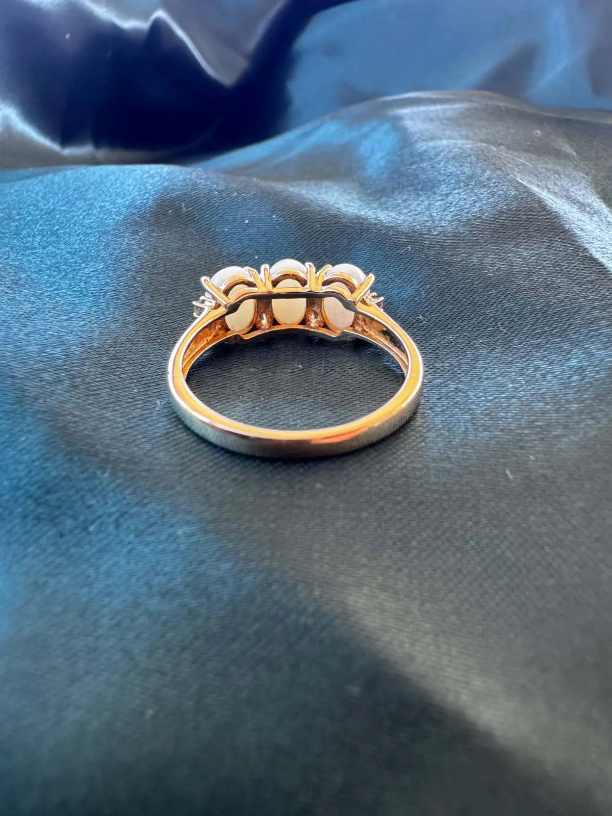 Three-stone white opal ring in 9ct yellow gold, reverse view showing the gold band interior and claw settings