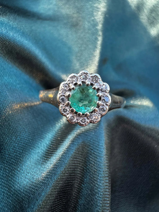 Emerald and diamond halo ring in 9ct yellow gold, overhead view showing round emerald surrounded by diamond halo