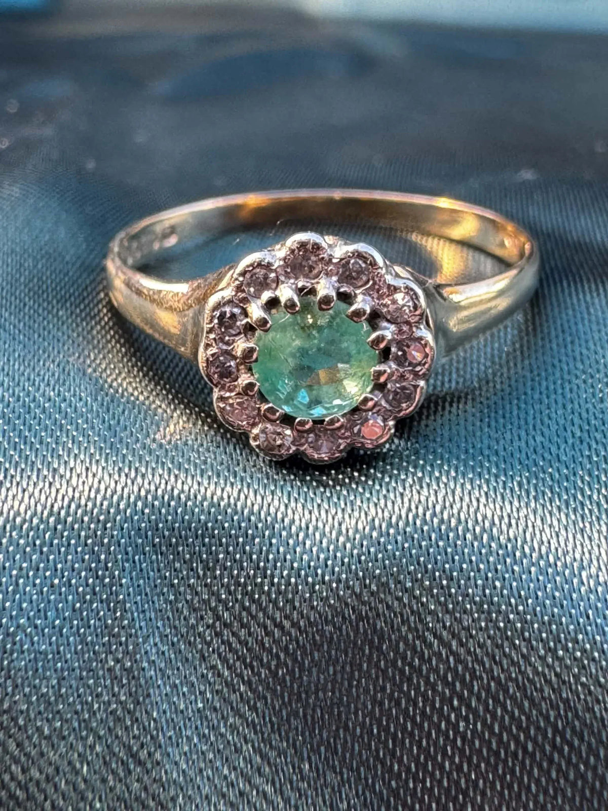 Emerald and diamond halo ring in 9ct yellow gold, three-quarter view showing emerald, diamond halo and gold band