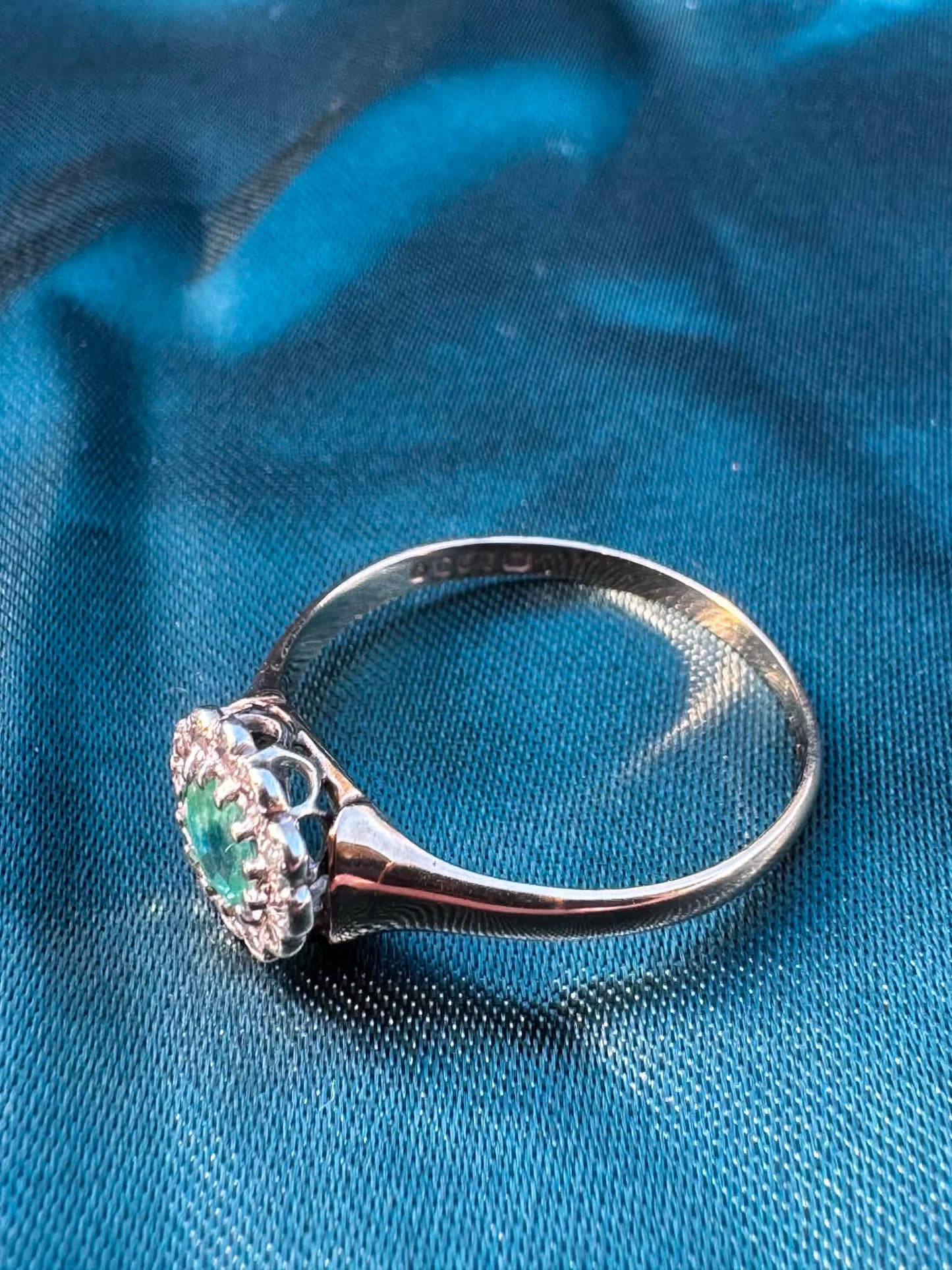 Emerald and diamond halo ring in 9ct yellow gold, top angled side view showing diamond cluster and gold band

