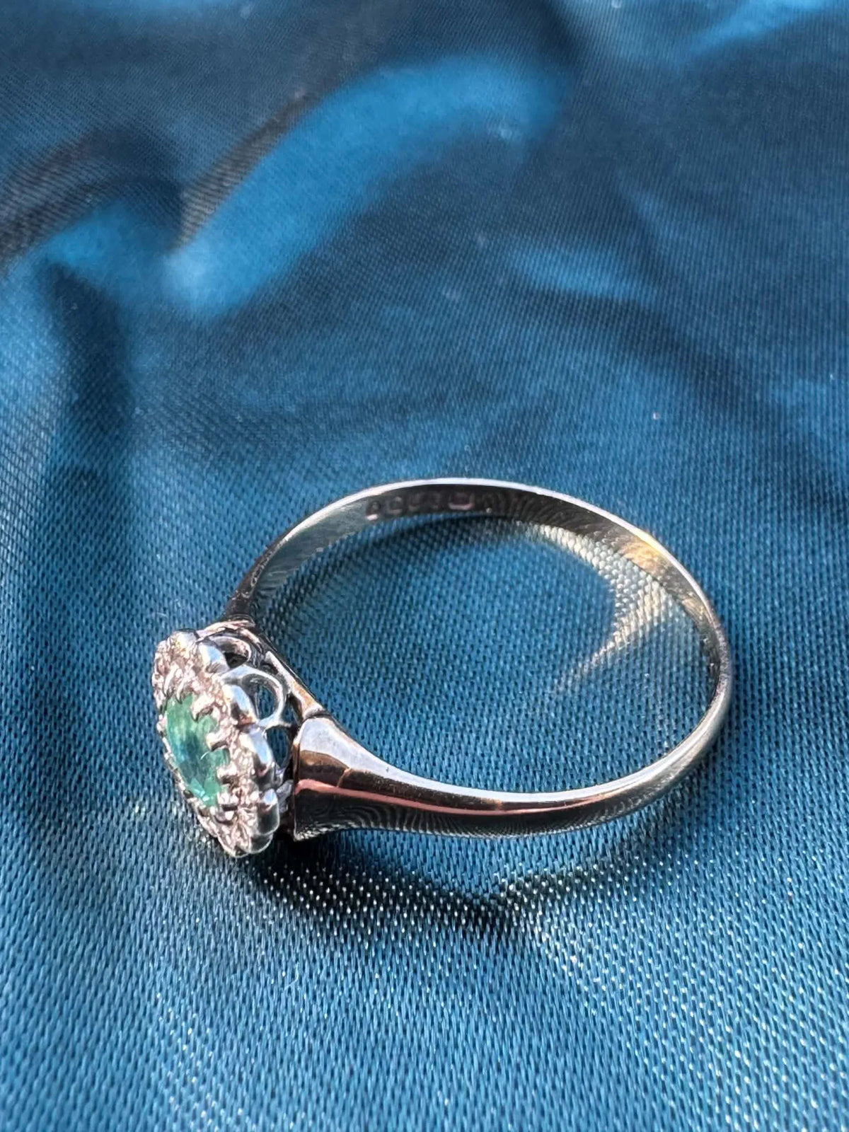 Emerald and diamond halo ring in 9ct yellow gold, top angled side view showing diamond cluster and gold band
