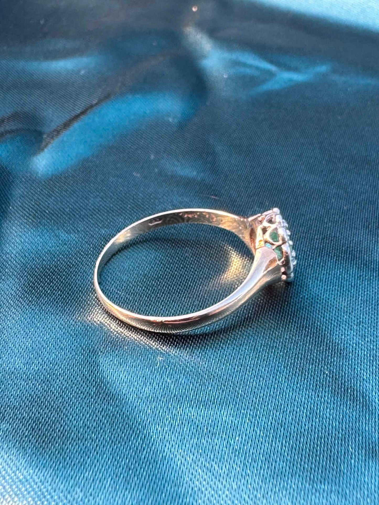Emerald and diamond halo ring in 9ct yellow gold, top side angle showing diamond halo and gold band