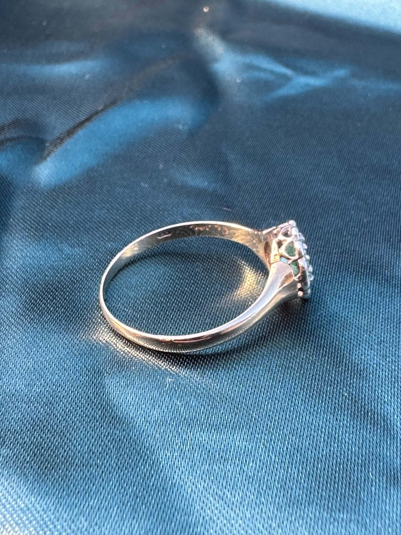 Emerald and diamond halo ring in 9ct yellow gold, top side angle showing diamond halo and gold band