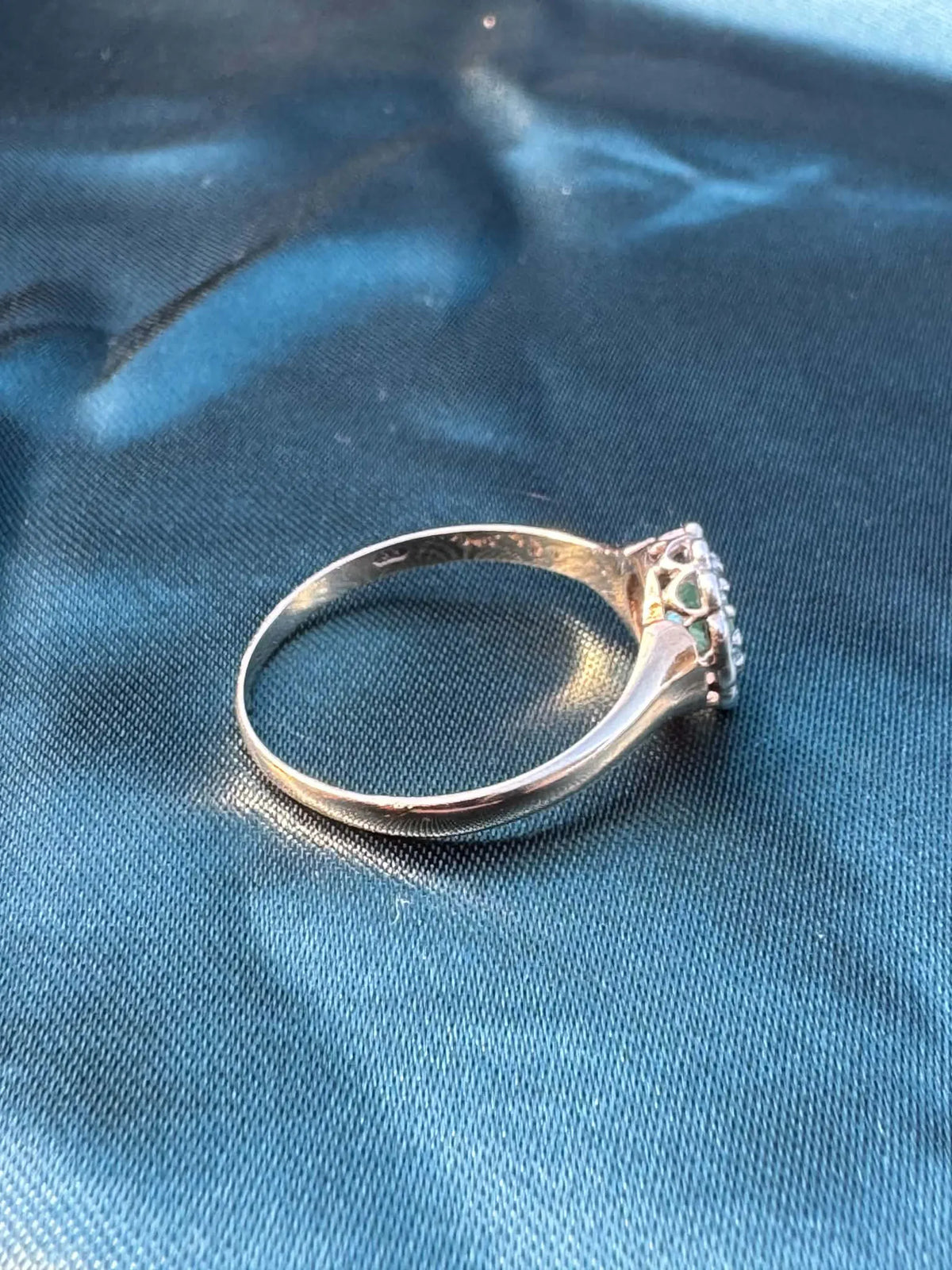 Emerald and diamond halo ring in 9ct yellow gold, top side angle showing diamond halo and gold band