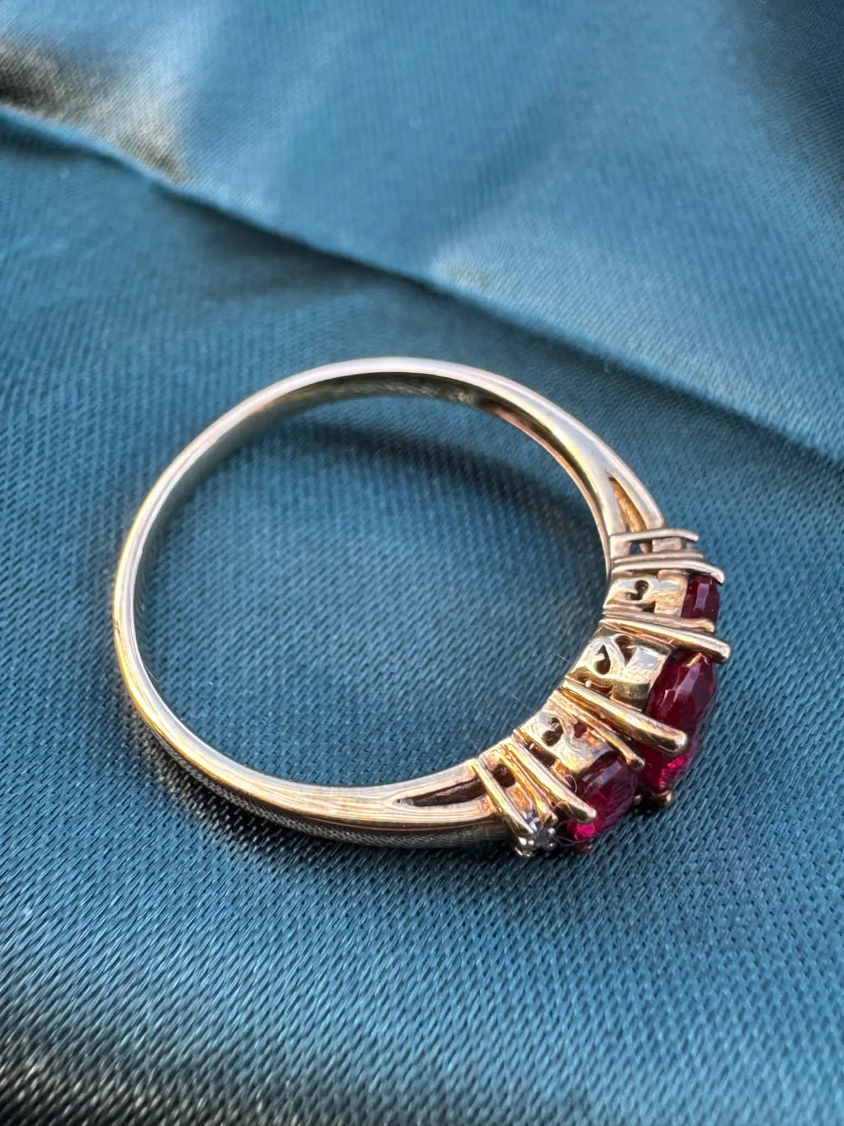 Ruby and diamond trilogy ring in 9ct yellow gold, angled view showing rubies facing down
