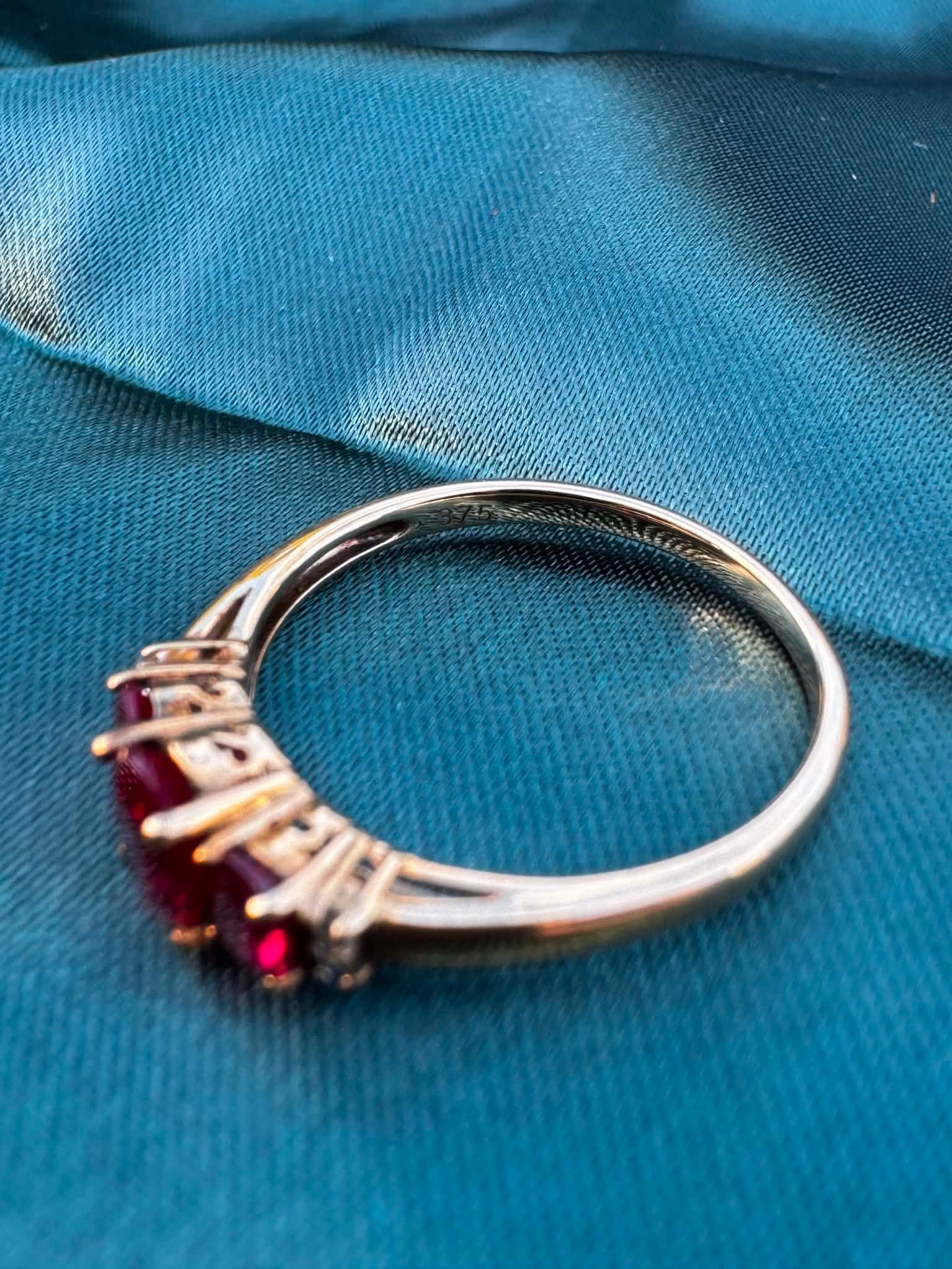 Ruby and diamond trilogy ring in 9ct yellow gold, angled view showing rubies facing down