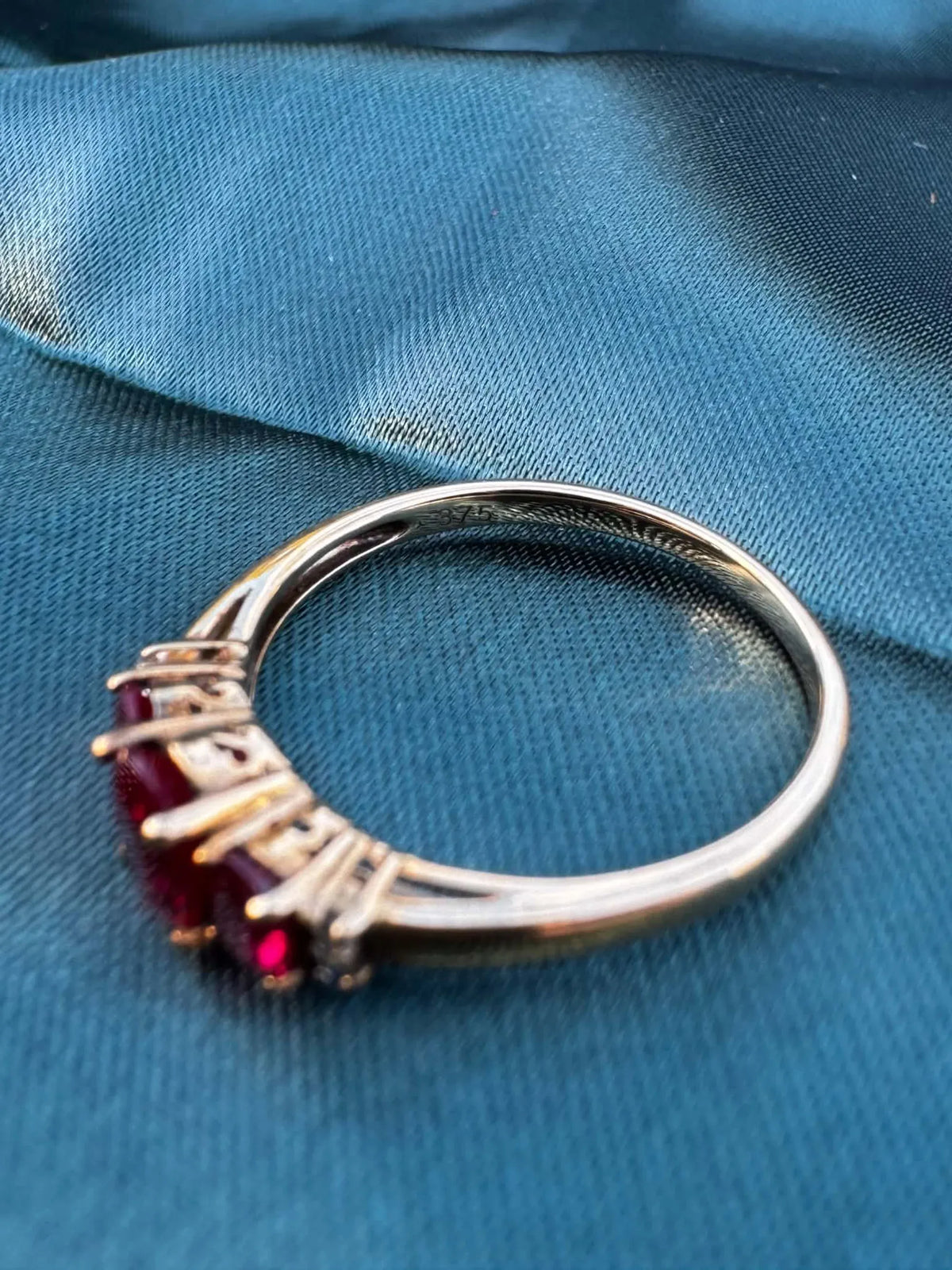 Ruby and diamond trilogy ring in 9ct yellow gold, angled view showing rubies facing down