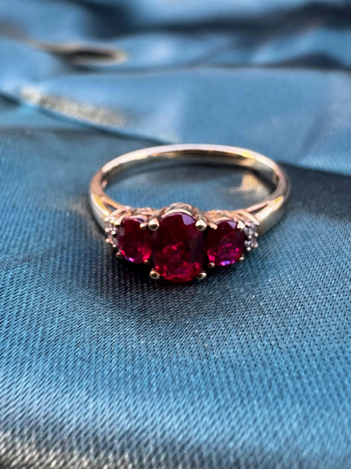 Ruby and diamond trilogy ring in 9ct yellow gold, front view showing three oval rubies
