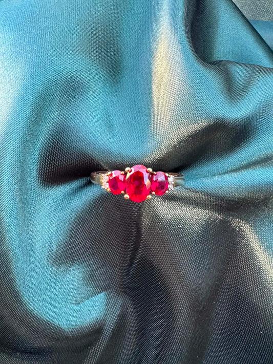 Ruby and diamond trilogy ring in 9ct gold, front view showing three oval rubies