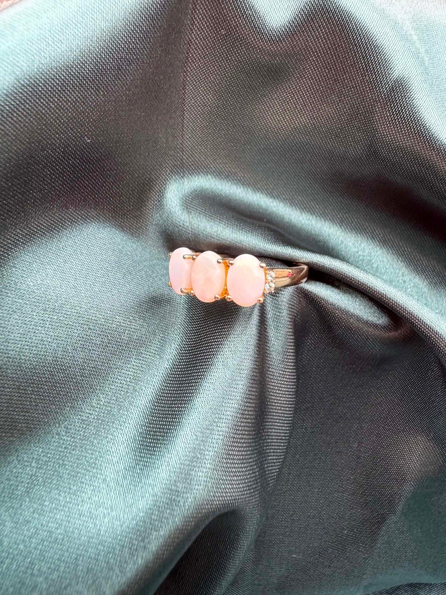 Three-stone white opal ring in 9ct yellow gold, angled front view showing white opal and green accent gemstones