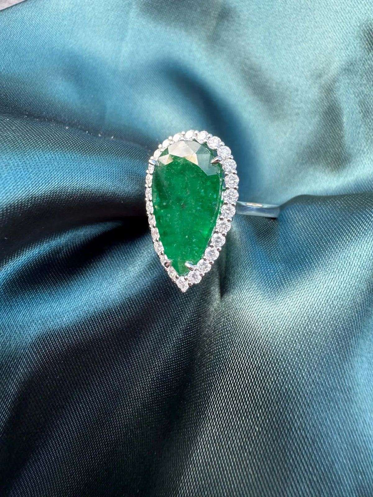 8.28ct pear emerald and diamond halo ring in platinum, angled front view showing pear emerald and diamond halo
