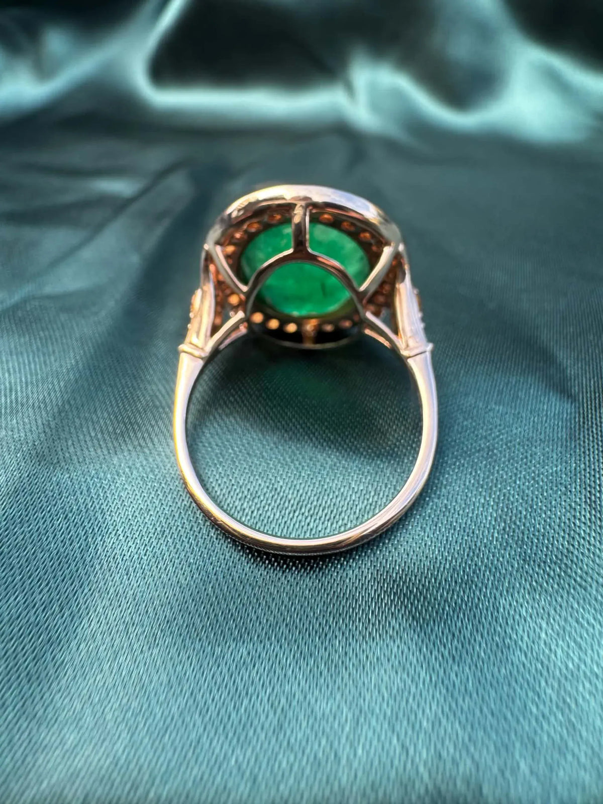 Emerald and orange sapphire cocktail ring in 14ct rose gold, underside view showing basket setting