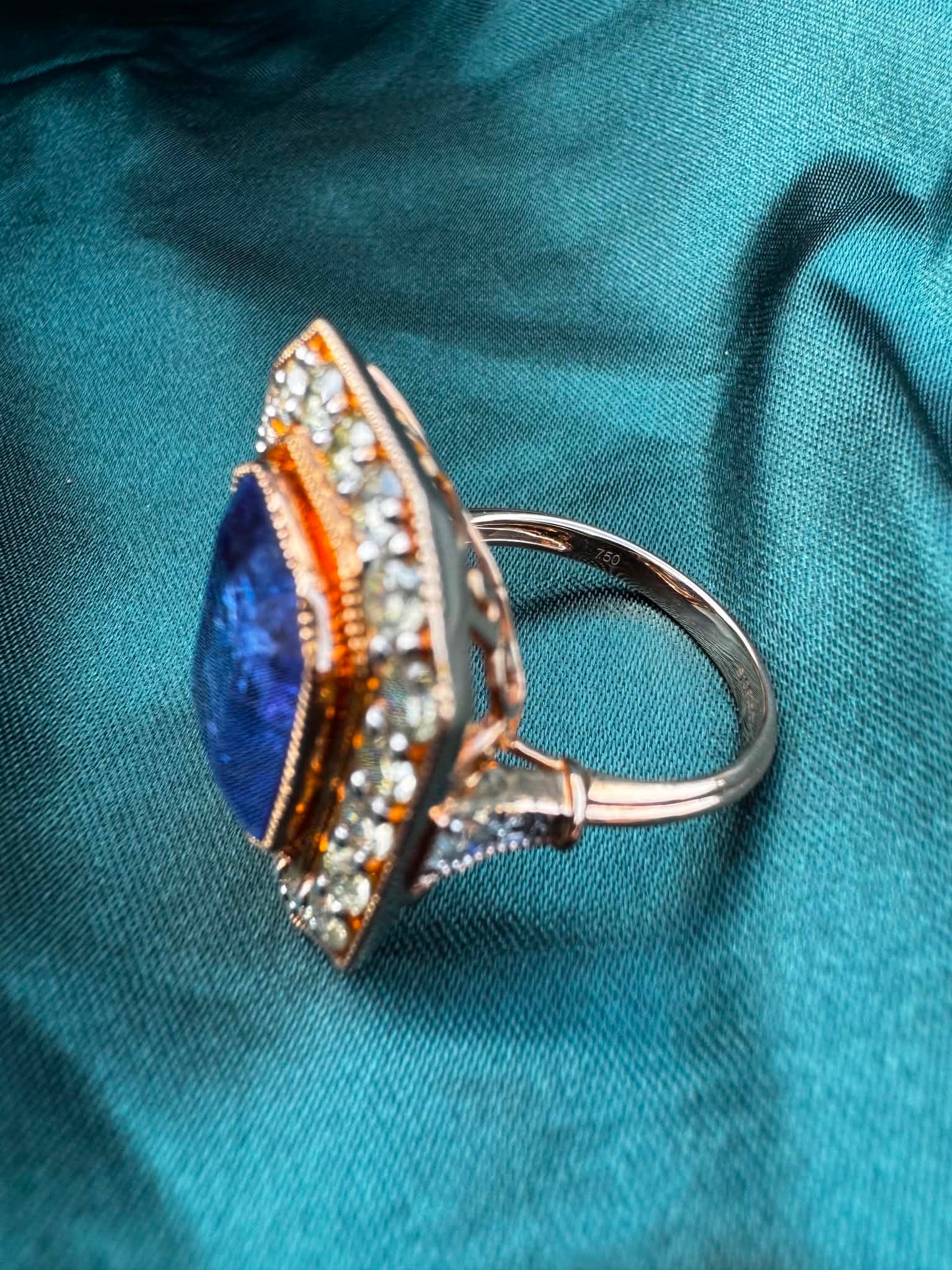 Tanzanite and diamond halo ring in 18ct rose gold, angled side view showing band and diamond halo