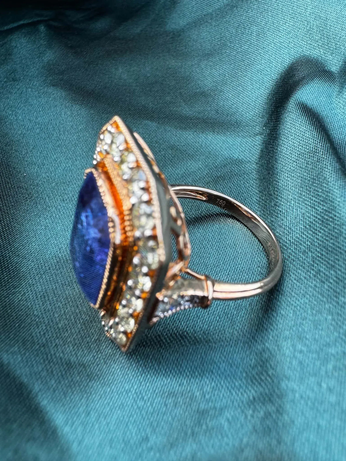 Tanzanite and diamond halo ring in 18ct rose gold, angled side view showing band and diamond halo