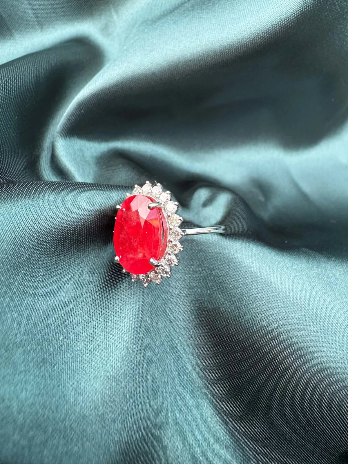 Ruby and diamond halo ring in platinum, angled view showing oval ruby in diamond halo setting