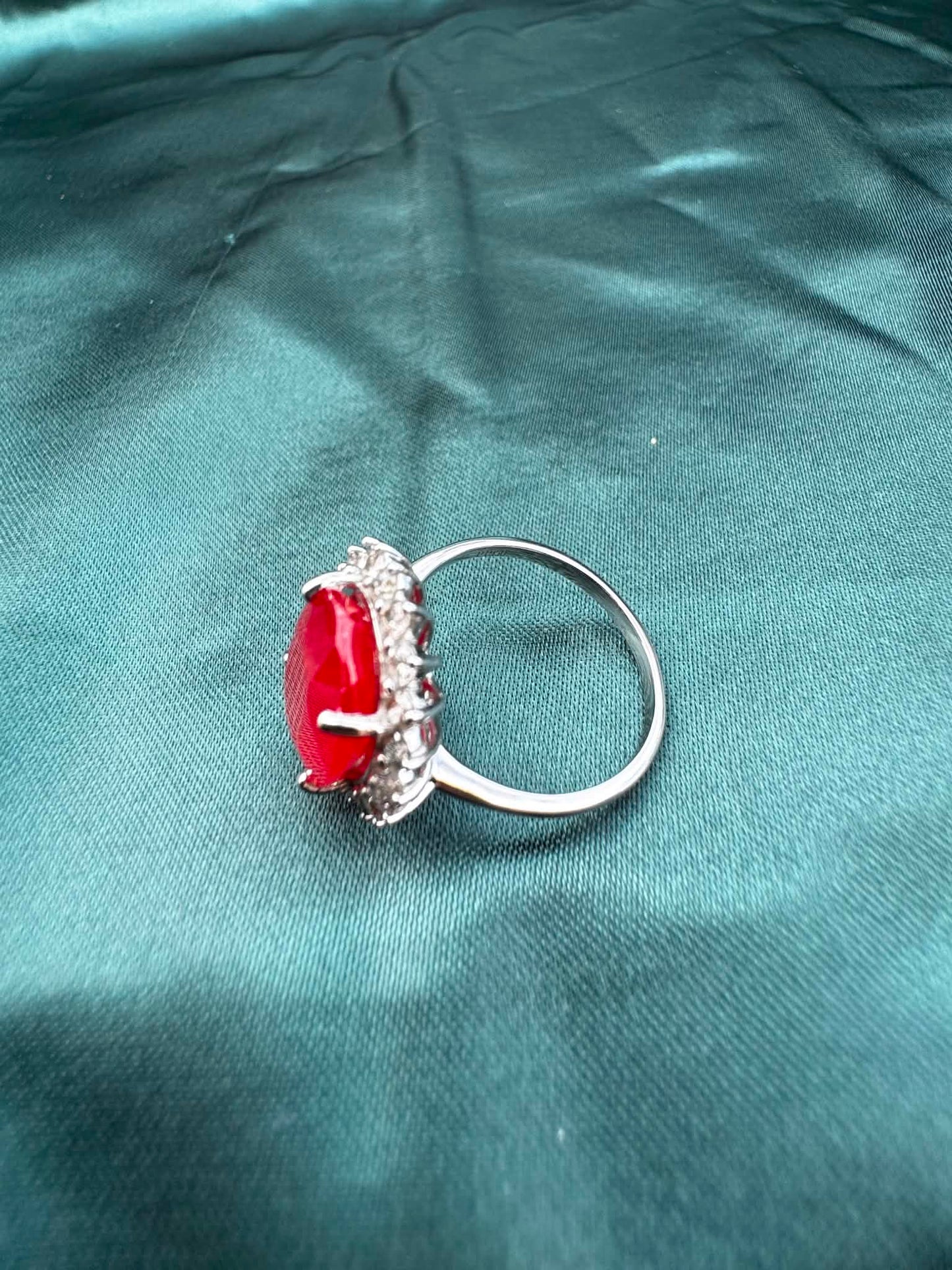 Ruby and diamond halo ring in platinum, angled top-side view showing oval ruby in diamond halo setting