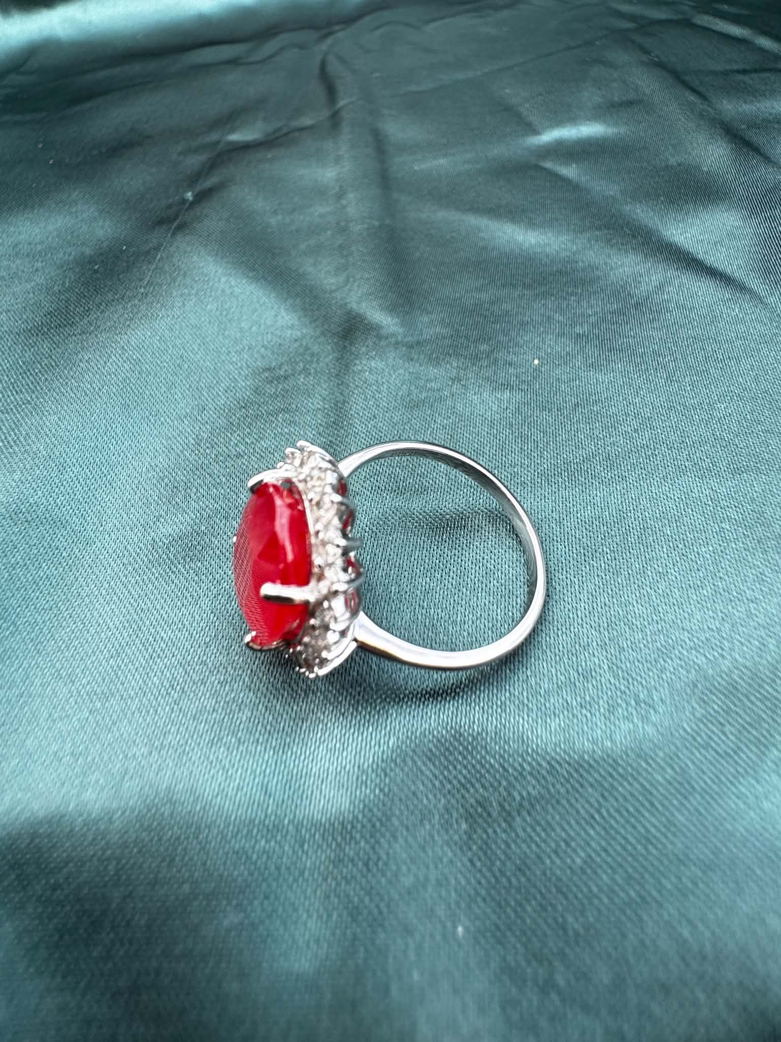 Ruby and diamond halo ring in platinum, angled top-side view showing oval ruby in diamond halo setting
