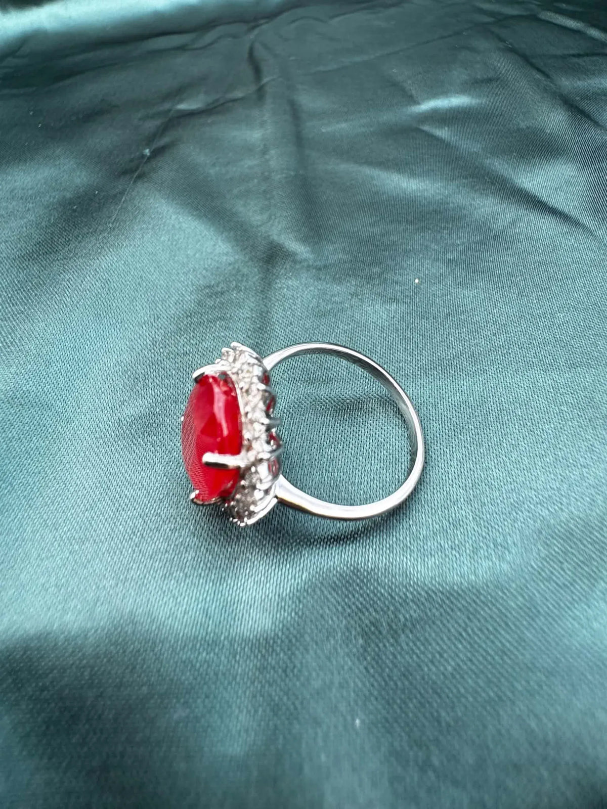 Ruby and diamond halo ring in platinum, angled top-side view showing oval ruby in diamond halo setting