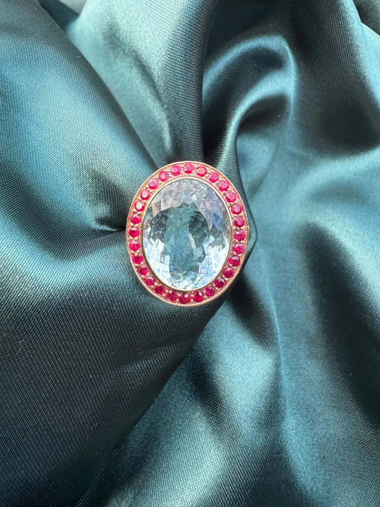 Aquamarine and gemstone halo ring in 14ct rose gold, front view showing oval aquamarine and red gemstone halo