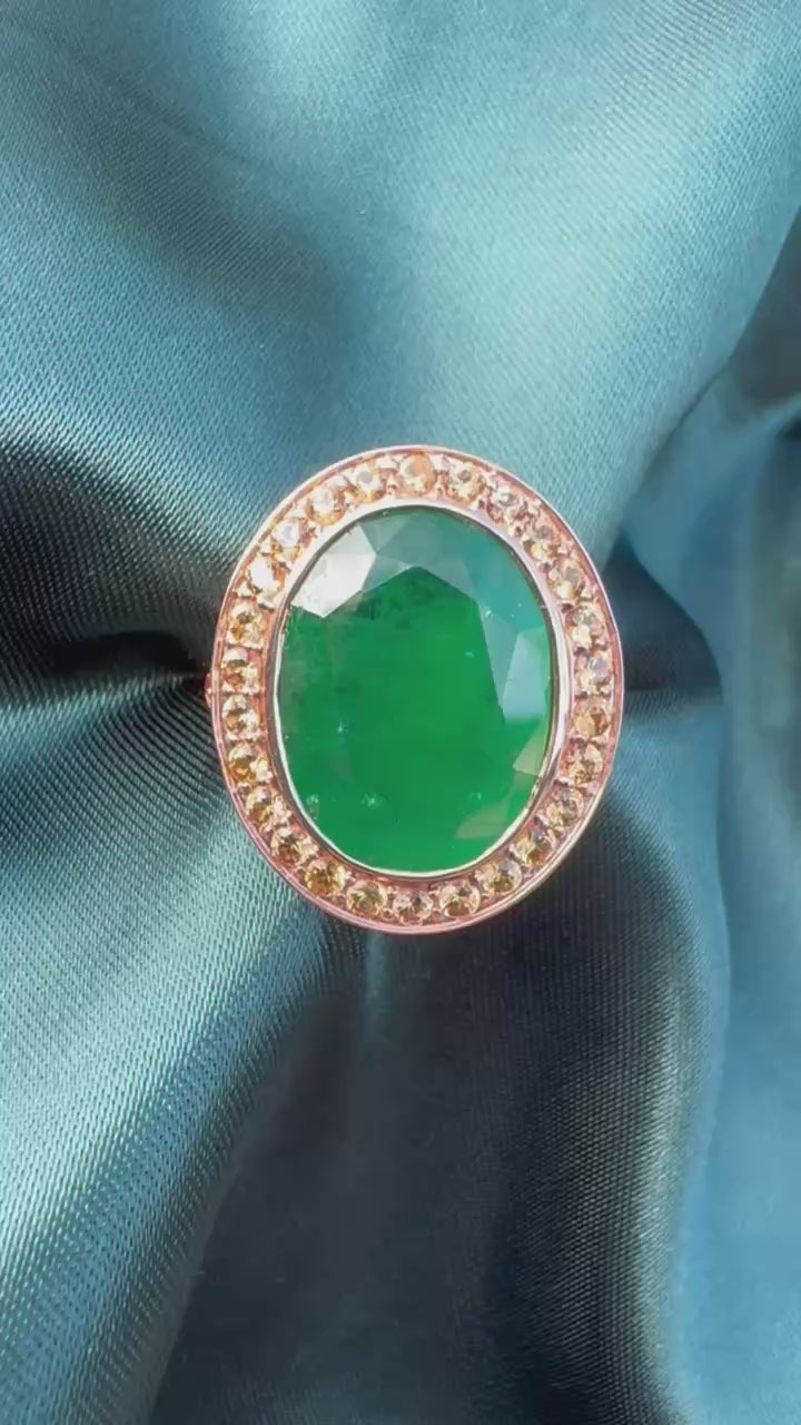 Emerald and orange sapphire cocktail ring in 14ct rose gold, front view showing oval emerald and sapphire halo