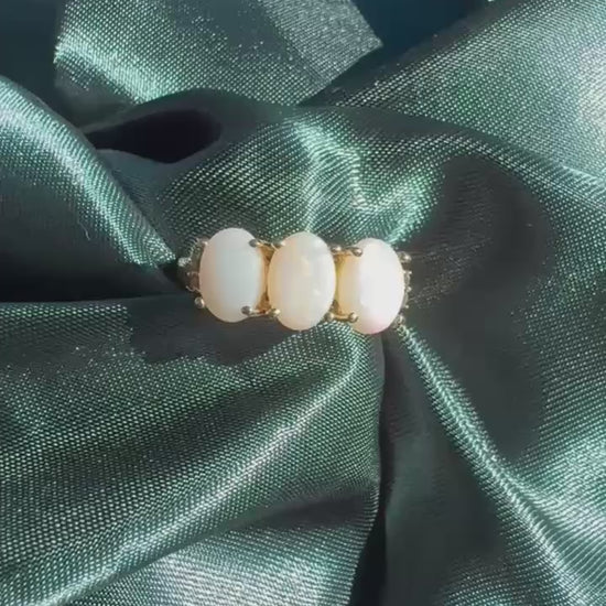 Three-stone white opal ring in 9ct yellow gold, top view showing three oval white opal cabochons in yellow gold claw settings video