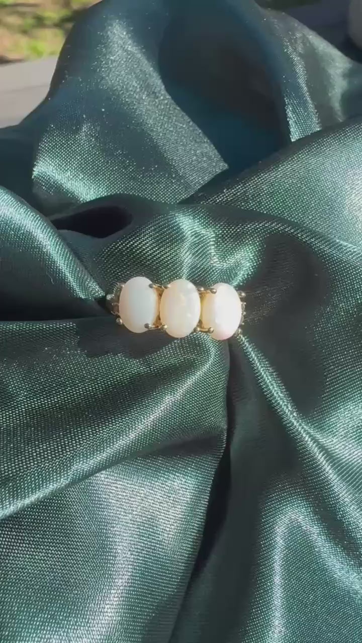 Three-stone white opal ring in 9ct yellow gold, top view showing three oval white opal cabochons in yellow gold claw settings video